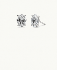 Pair of silver-tone Muse oval stud earrings, one facing forward and the other angled to show the setting and bare post, on an ivory background.