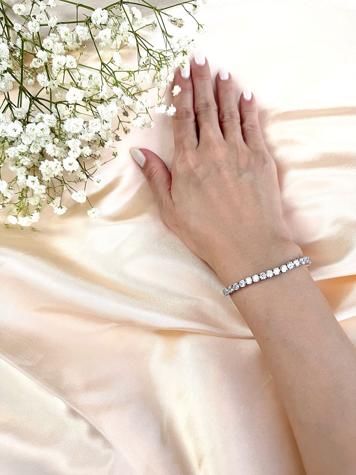 Jaguarlily diamond-look tennis bracelet on wrist with soft satin background
